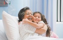 Grandmother in hospital bed hugging her granddaughter